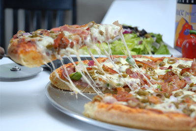 A Milano pizza with a cheesy slice being lifted